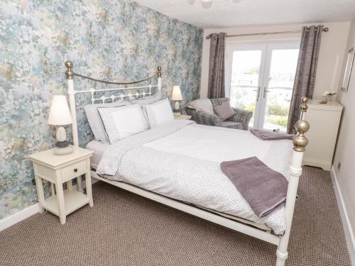 a bedroom with a white bed and a window at Harbour View in Cemaes Bay