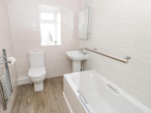 a white bathroom with a toilet and a sink at Harbour View in Cemaes Bay
