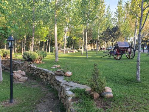 a stone wall with a carriage in a park at HOTEL MASIA EL MOLINETE in Mora de Rubielos