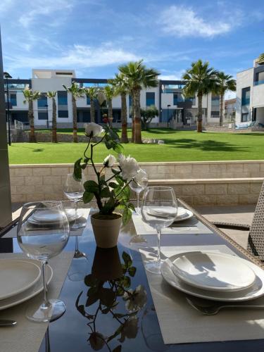 uma mesa com copos e um vaso com flores em OASIS BEACH apartments em Alicante