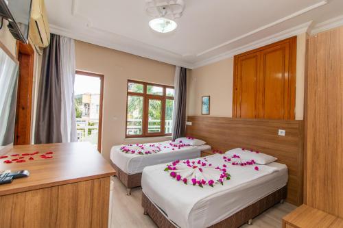 two beds in a hotel room with pink flowers on them at Castello Hotel & Aparts in Kemer