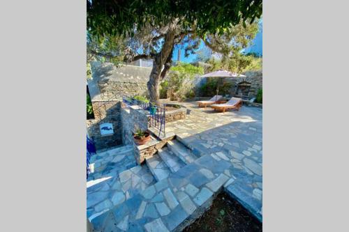 un patio de piedra con un banco y un árbol en Πέτρινη αυλή, Αρμενιστης Ικαρια, en Armenistis