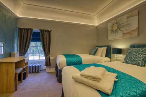 um quarto de hotel com duas camas e uma secretária em Golspie Inn em Backies