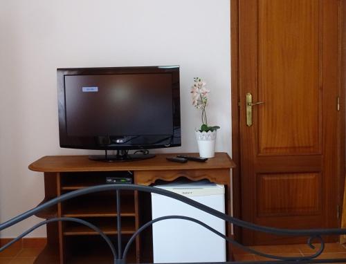 a television sitting on a wooden stand with a table at MIRA VILA by Stay in Alentejo for HIKERS in Vila Nova de Milfontes
