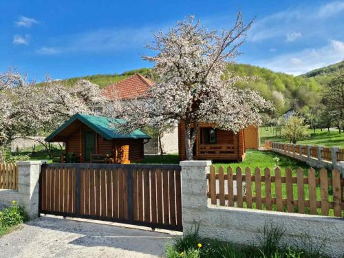 a wooden fence in front of a house with a tree at Guest house Green Garden in Mojkovac