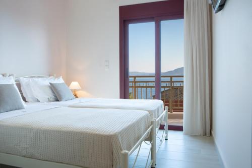 two beds in a hotel room with a balcony at Nikolas Guest House Villa in Nikiana