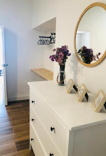 a white dresser with a vase of flowers and a mirror at Damajuana in Níjar