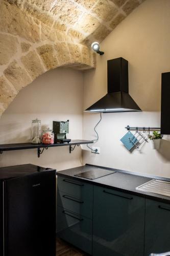 a kitchen with black cabinets and a stone wall at Dimora 19.92 in Monopoli