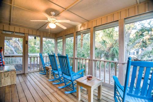 a porch with blue chairs and a table and windows at Slow Drift in Edisto Beach
