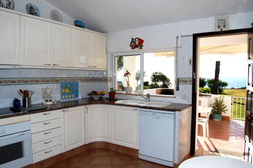 a kitchen with white cabinets and a view of the ocean at Ocean facing at Senhora da Rocha in Porches