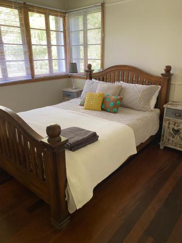 um quarto com uma grande cama de madeira com almofadas em Coochin Cottage, Beerwah em Beerwah