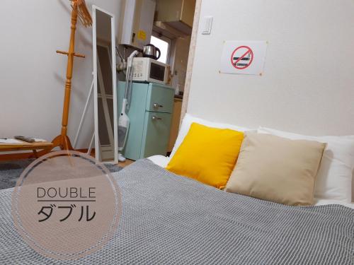 - une chambre avec un lit et un oreiller jaune dans l'établissement Luxes Hiroshima2F ラクセス ヒロシマ2F, à Hiroshima