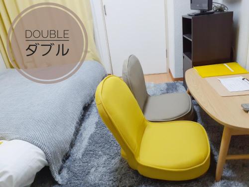 une chambre avec une chaise jaune et une table dans l'établissement Luxes Hiroshima2F ラクセス ヒロシマ2F, à Hiroshima