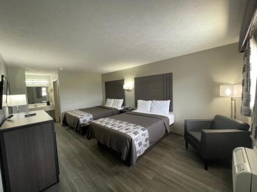 a hotel room with two beds and a chair at Embassy Inn - Hohenwald in Hohenwald