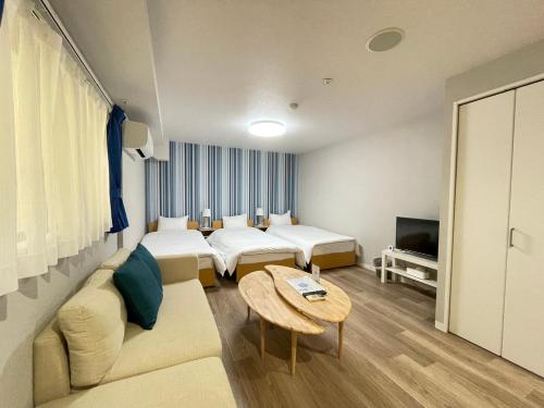 a room with two beds and a couch and a table at Guest House Laule'a Tennoji in Osaka