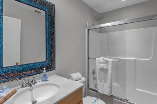 uma casa de banho com um lavatório e um chuveiro com um espelho. em The Tequila Sunrise at Lazy Way em Fort Myers Beach