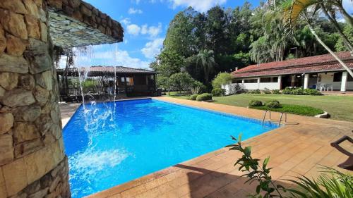 a swimming pool with a waterfall in a yard at Pousada Recanto Por do Sol in Morungaba