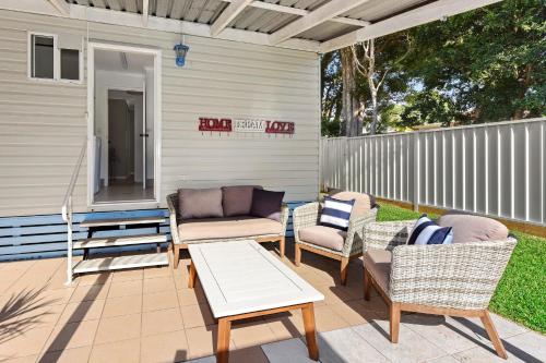 a patio with chairs and a table and a couch at Flynns Beach Caravan Park in Port Macquarie