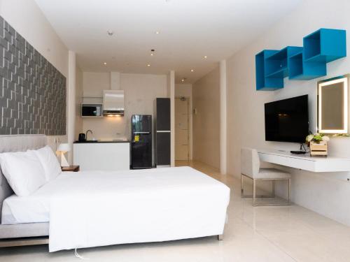 a bedroom with a white bed and a kitchen at City Park Hotel Residences in Manila