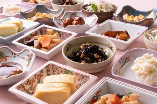 a table topped with bowls of different types of food at Iga Ueno City Hotel in Iga