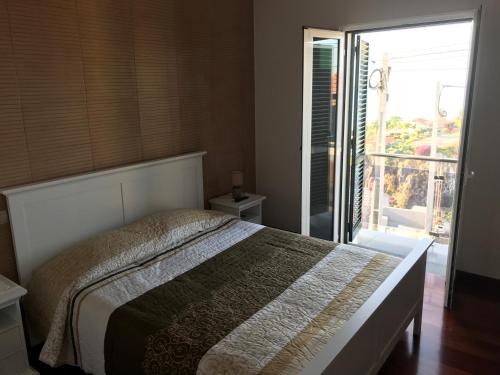 a bedroom with a bed and a door to a balcony at Ammy’s House in Câmara de Lobos