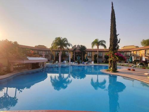 une grande piscine bordée de palmiers et un bâtiment dans l'établissement Gran Hotel Hacienda De La Noria, à Aguascalientes