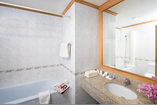 a bathroom with a sink and a tub and a mirror at Riverine Place Hotel and Residence in Nonthaburi