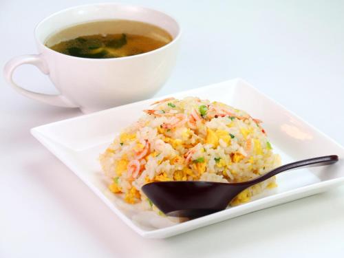 a plate of rice with a spoon and a cup of soup at Pension Kobekko in Otari