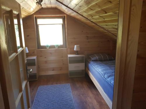 sypialnia w drewnianym domku z łóżkiem i oknem w obiekcie Domek Na Roztoczu w mieście Tomaszów Lubelski