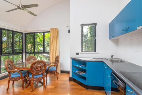 a kitchen with blue cabinets and a table and chairs at Dreamcatcher Beach-Side Apartments in Port Douglas