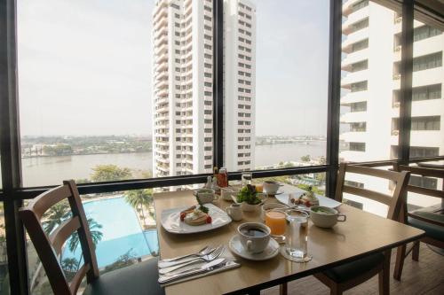 a table with food on it with a view of a building at Riverine Place Hotel and Residence in Nonthaburi