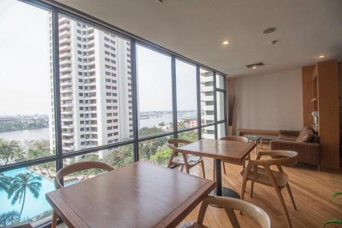 a room with tables and chairs and a large window at Riverine Place Hotel and Residence in Nonthaburi