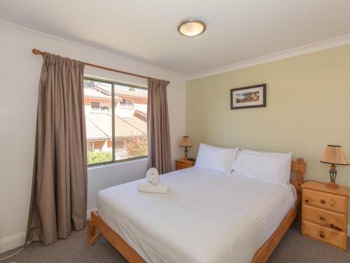 Schlafzimmer mit einem großen weißen Bett und einem Fenster in der Unterkunft Cobb and Co 3 39 Cobbon Cres in Jindabyne