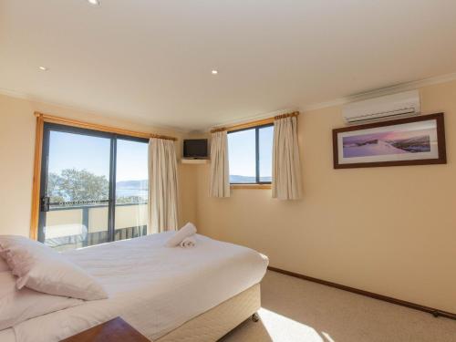 Un dormitorio con una cama y una ventana grande. en Lakehaus 2 of 11 Rainbow Drive, en Jindabyne