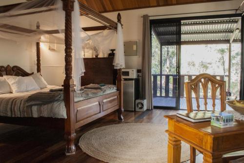 a bedroom with a canopy bed and a table and a chair at Barrabup Sanctuary BirdHide in Nannup