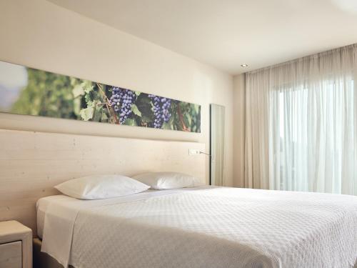 a bedroom with a white bed and a large window at Ionian Hill Hotel in Argasi