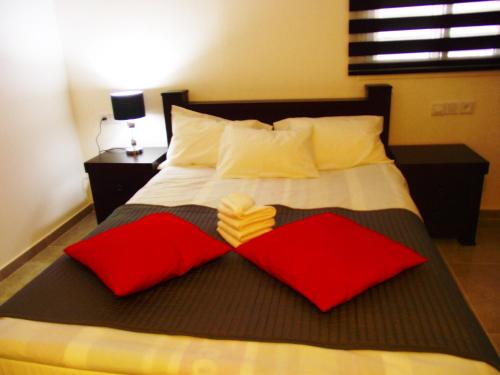 a bedroom with a bed with red and white pillows at City Apartments in Eilat