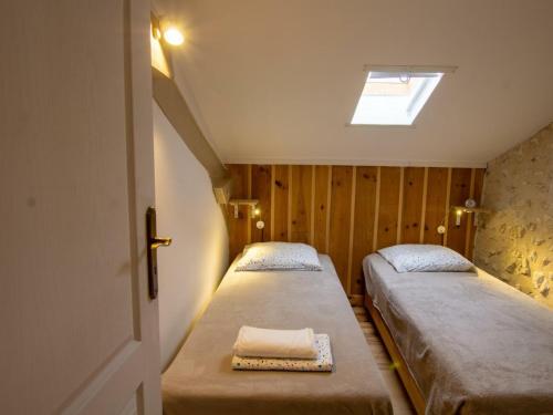 two beds in a small room with a skylight at Maison de campagne avec piscine, proche de Périgueux – 2 chambres, BBQ, activités variées à proximité - FR-1-616-54 in Mensignac