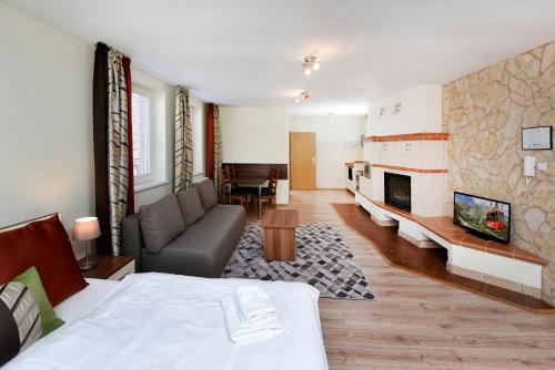 a bedroom with a bed and a couch and a fireplace at APLEND Vila Júlia in Vysoke Tatry - Tatranska Lomnica.