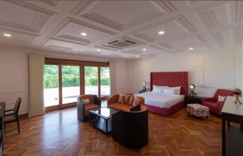 um quarto de hotel com uma cama, um sofá e cadeiras em Glenville Forest Resort & Spa em Dehradun