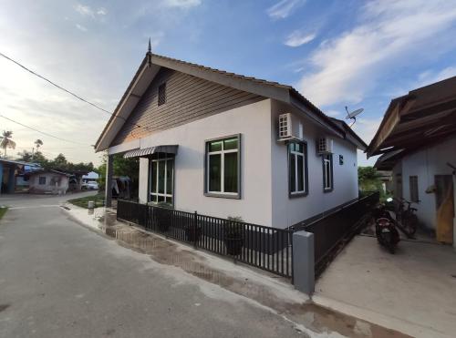 uma pequena casa branca com uma cerca preta em Desa Hana Homestay em Kuala Terengganu