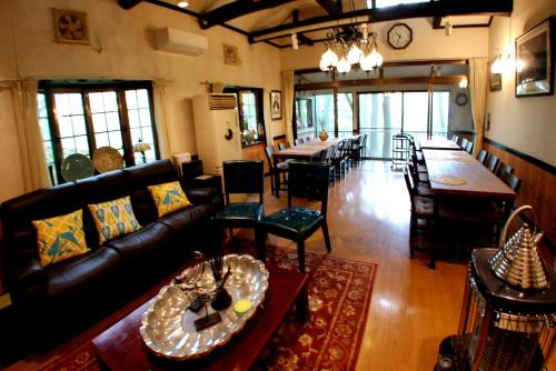 uma sala de estar com um sofá, mesas e cadeiras em Gableview Forest Inn ゲーブルビュー em Nikko