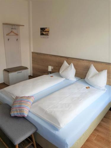 Cette chambre comprend un grand lit blanc et une chaise. dans l'établissement Pension Förster, à Glauchau