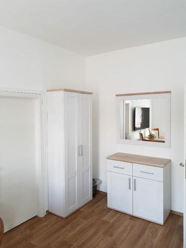 eine Küche mit weißen Schränken und einem Spiegel in der Unterkunft Pension Förster in Glauchau