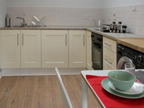 a kitchen with white cabinets and a bowl on a table at Hugh O'Neill Ambassador Suite in Dungannon