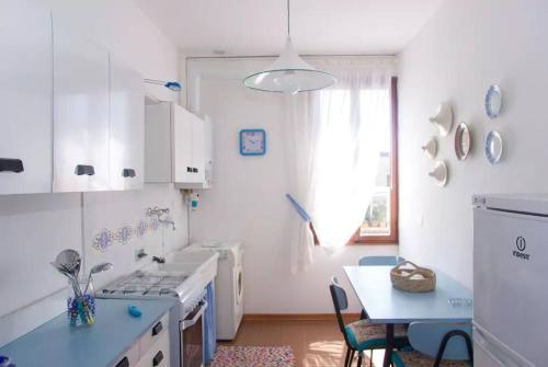 a kitchen with white cabinets and a table with a blue counter top at Palazzo Baffo - Residenza storica , Chioggia in Chioggia