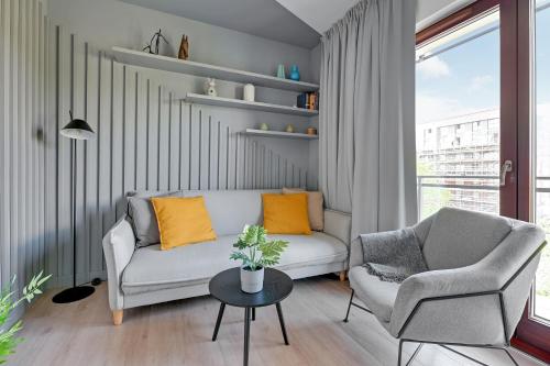 een woonkamer met een bank, een stoel en een tafel bij Aura III Apartments & Free Parking by Downtown Apartments in Gdańsk