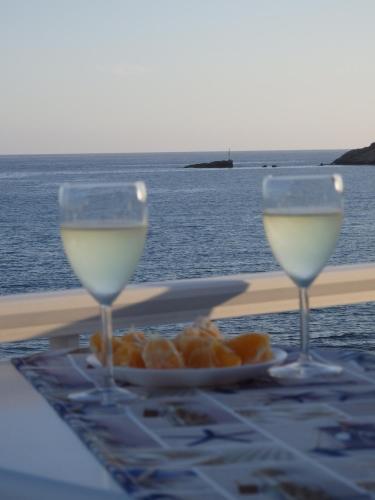 two glasses of white wine sitting on a table near the ocean at Coastal Apartment Christina 2 in Makry Gialos