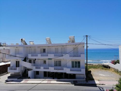 a white apartment building with the ocean in the background at Coastal Apartment Christina 2 in Makry Gialos
