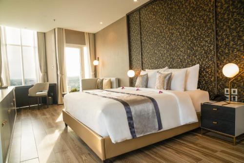 a hotel room with a large bed and a desk at Diamond Stars Ben Tre Hotel in Ben Tre